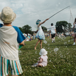 Children having fun at an outdoor event, with bubbles.