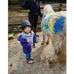 A small child, who is grinning, standing next to a white pont.