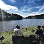 Two people sat by a lake, having a break while road cycling.