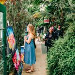 A woman looking at prints at Art in the Gardens 2025 