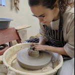 Person shaping clay on a pottery wheel in a workshop studio.