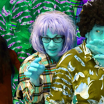 Promotional image for Cold Sweat featuring a man and woman with turquoise skin and contrasting hair colours. They wear colourful patterned shirts. Behind them, a woman with long black hair holds a cup. They stand against a green leafy background.
