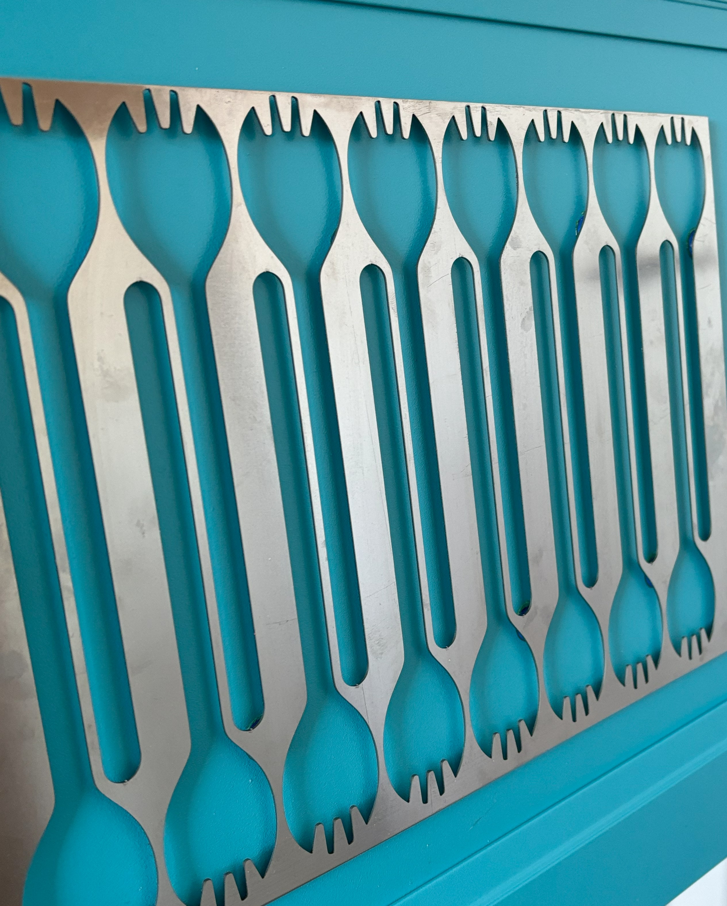 Abstract panel design with rows of curved green shapes cut into a silver metallic sheet, creating a modern, repetitive pattern.