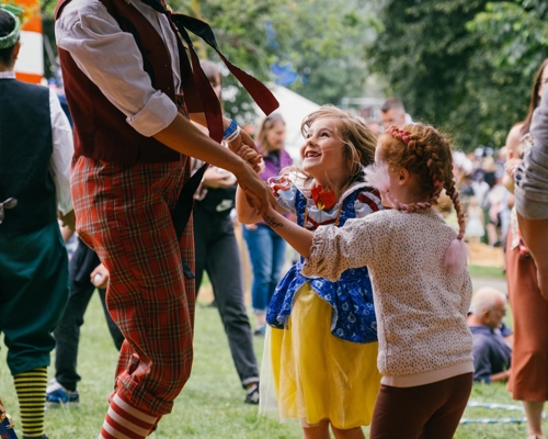 Two children dancing with a clown at the Tramlines Festival.