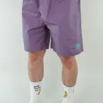 The lower half of a man, who is wearing purple shorts and white socks.