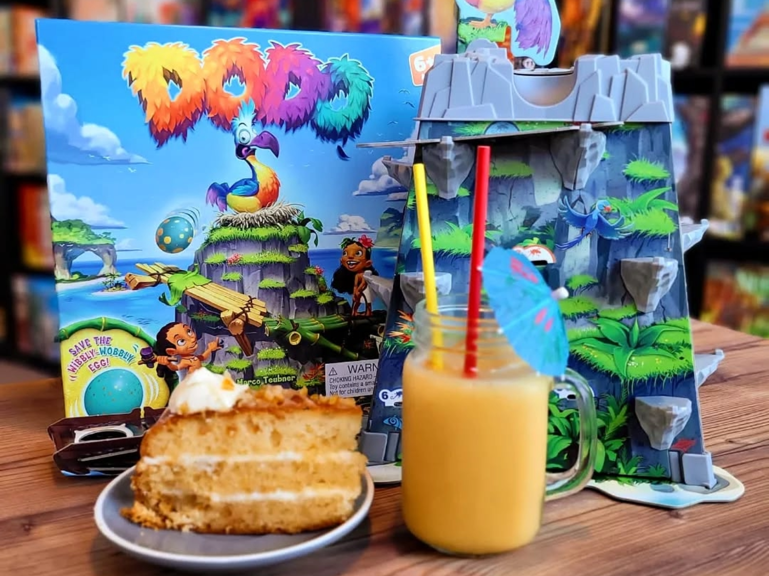 A table at The Dice Box Sheffield with a cocktail, a slice of cake and a game called Dodo.
