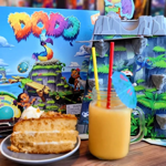 A table at The Dice Box Sheffield with a cocktail, a slice of cake and a game called Dodo.