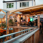 The covered balcony at Hagglers Corner, filled with people eating and drinking.