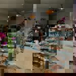 Insides Eve Kitchen. A person stands behind the counter. Inside a glass display case is a range of pastries and cakes.