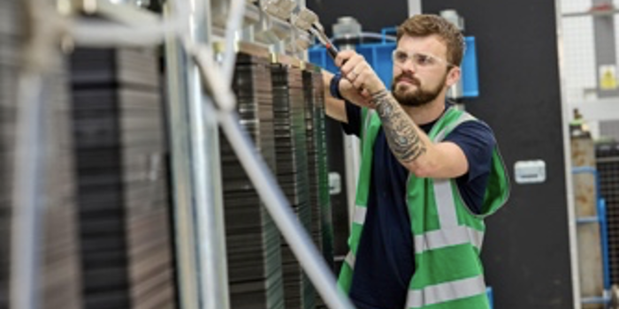A man in a green high viz vest is working on a piece of machinery.