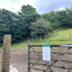An open gate leads into a fenced off grassy field at Rivelin Valley Dog Park.
