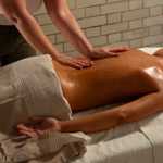 Someone laying on their front wile a therapist massages their back 