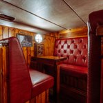 A bar booth with wood panelling and red leather upholstery. 