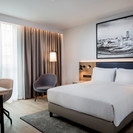 Modern bedroom with a double bed and a local picture hanging on the wall and cool lighting.