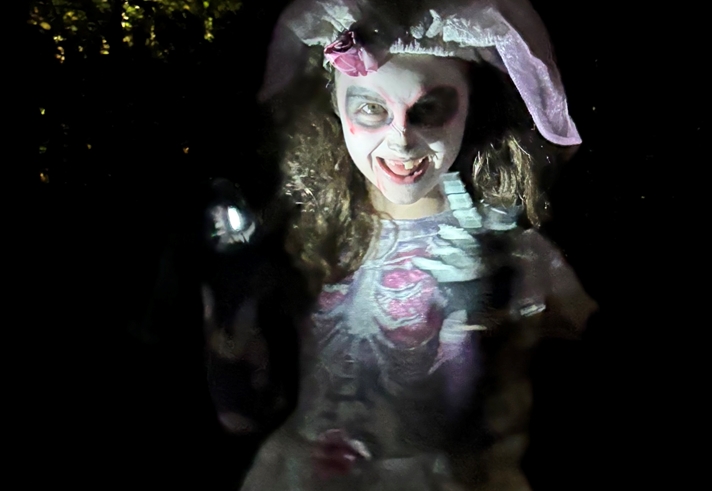 A young person in Halloween fancy dress lit with spooky lighting.