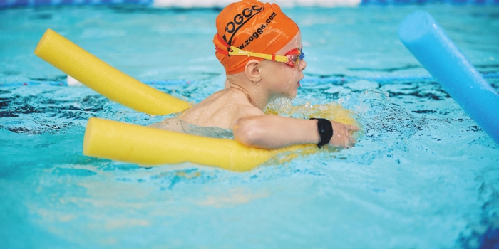 A child learning to swim in a swimming pool.