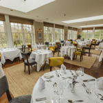 Bright and spacious restaurant with round tables and stylish décor at Losehill House Hotel.