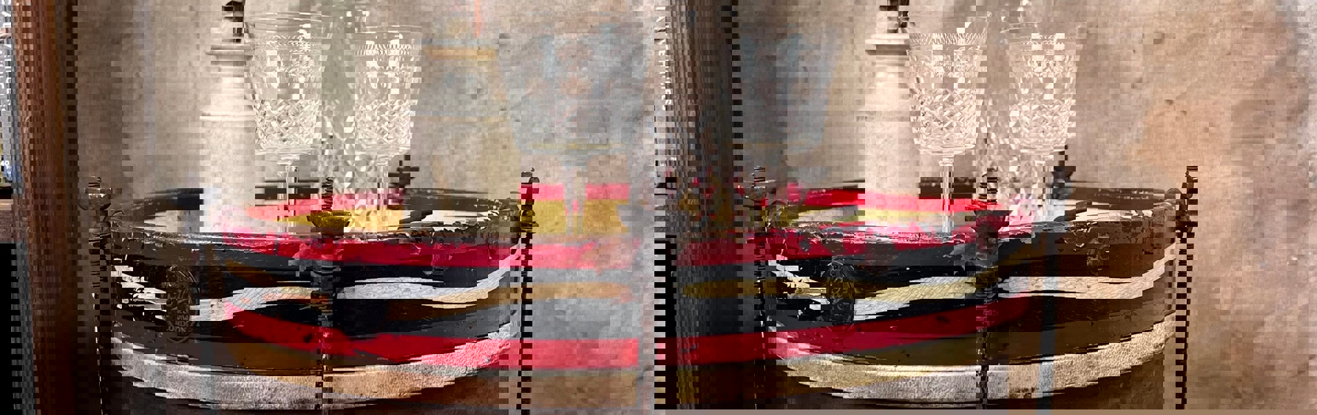 A bass drum lying on its side, on the floor, with a vase of flowers, a decanter and two glasses on top.