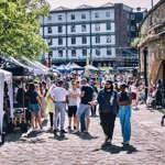 Sunny day as people walk along the cobbled quayside 