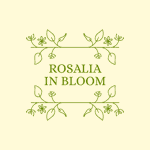 A minimalist logo design featuring the text “ROSALIA IN BLOOM” in green uppercase letters, framed by delicate green floral illustrations with leaves and small flowers on a pale yellow background.