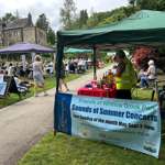 A food stall and rows of people in deckchairs watching an event in a park.