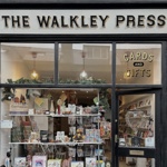 Front window display of The Walkley Press shop, showing cards, gifts, and books arranged inside, with the shop’s name displayed above the entrance.