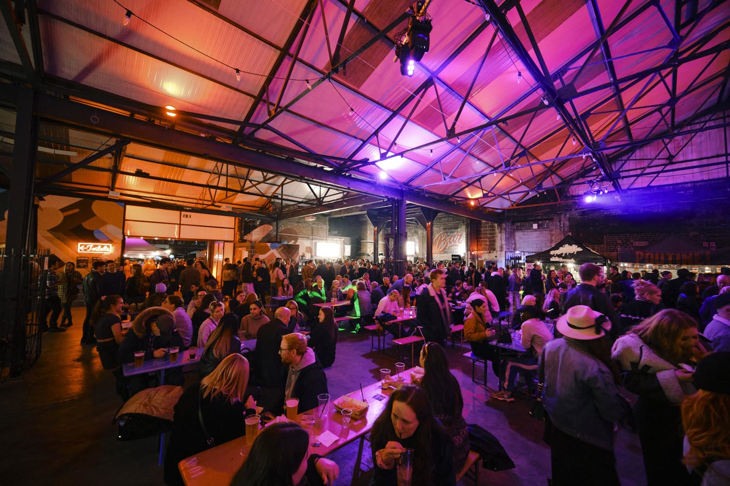 A view inside the Peddler market, there are lots of people seated at tables, eating and chatting.