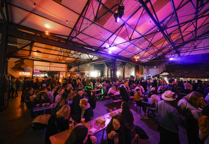 A view inside the Peddler market, there are lots of people seated at tables, eating and chatting.