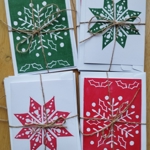 Four bundles of hand-made Christmas card, on a wooden table.