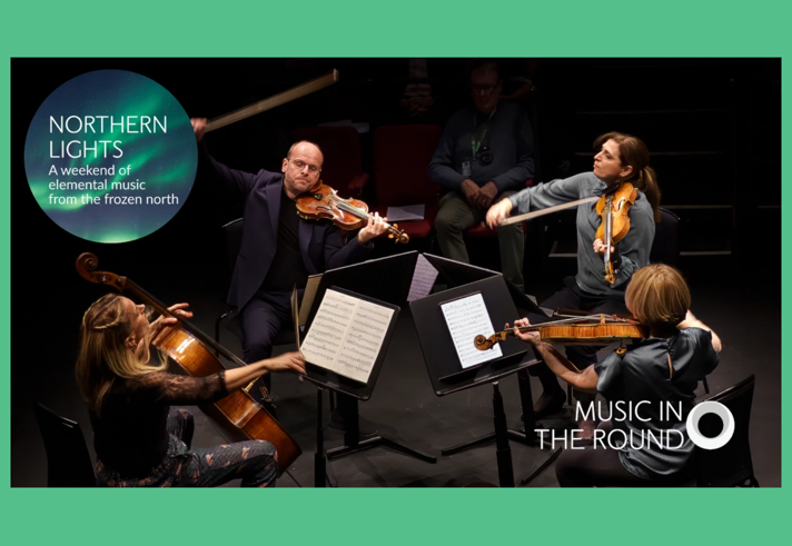 A string quartet, sat in a circle facing inwards, are performing on a stage.