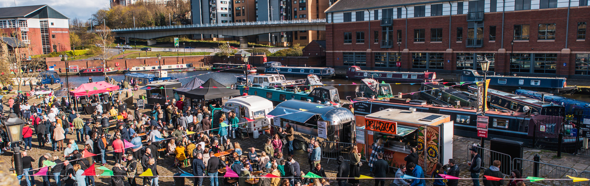 Quayside Market At Victoria Quays in full flow with people wandering about, in bright sunshine, and sitting at trestle tables eating.