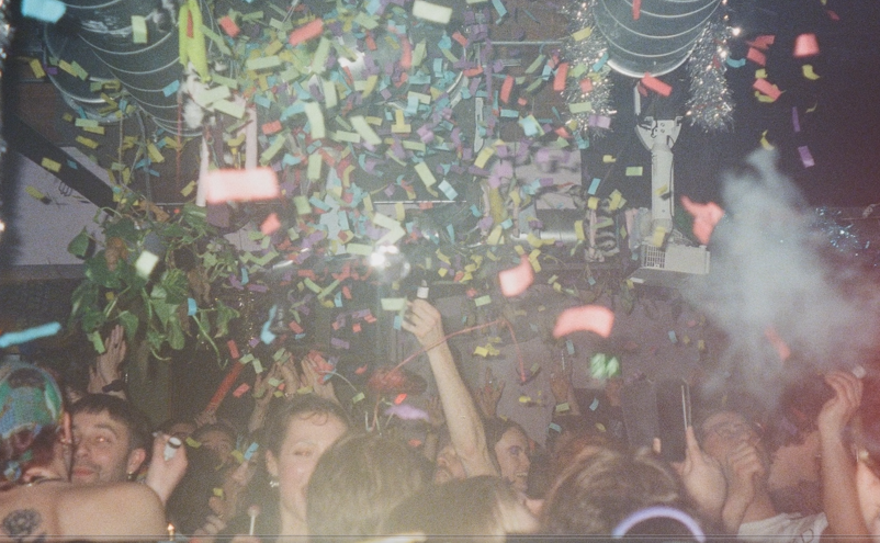 A jubilant scene with confetti falling from the ceiling as people dance at Gut Level