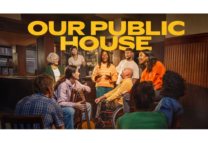A group of 10 people standing and sitting together in a pub setting.