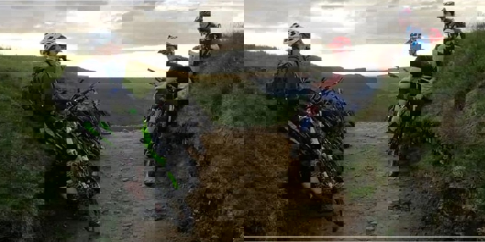 People mountain biking on a dirt track in the countryside.