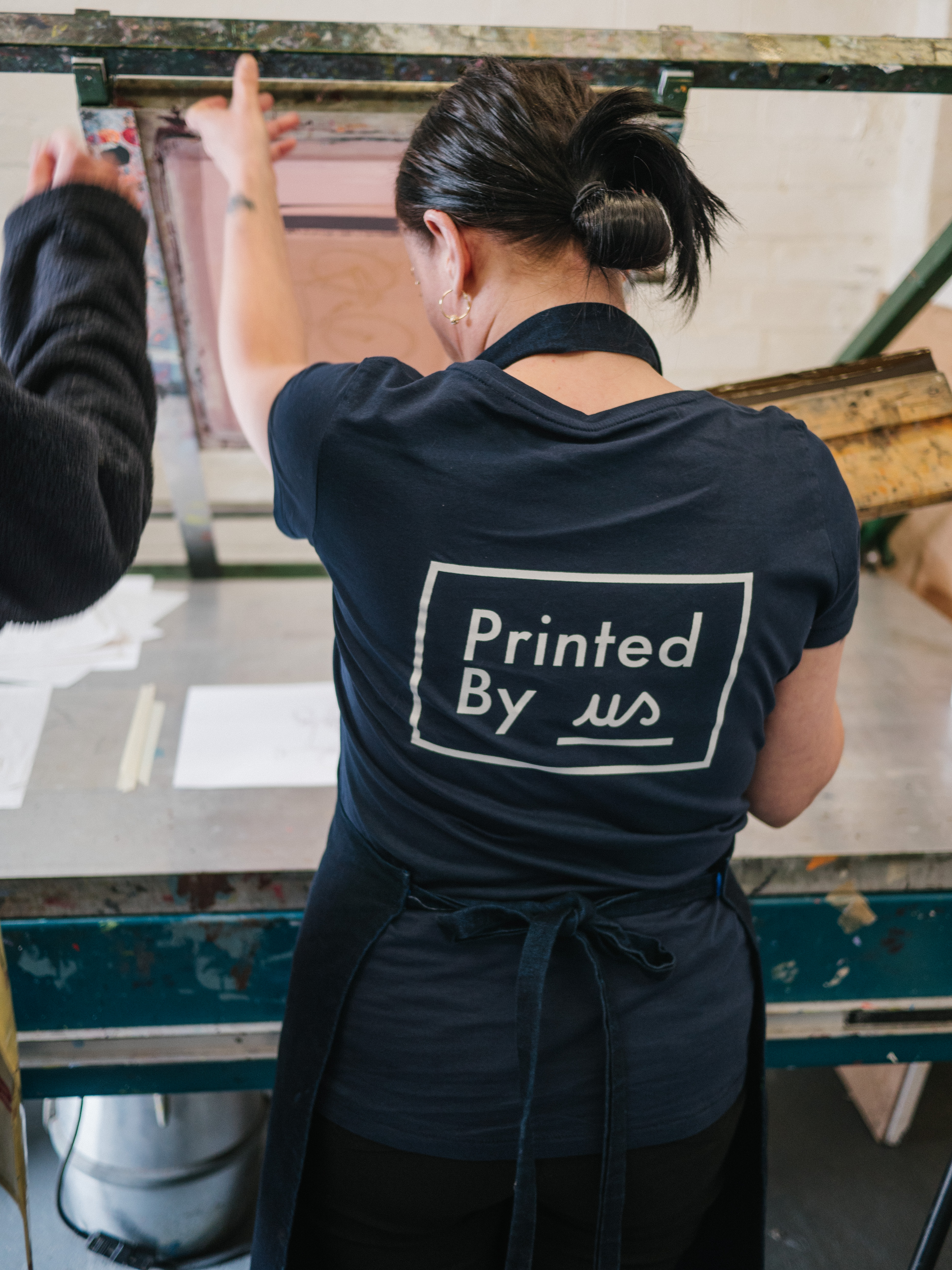 A woman screen printing at Printed by Us.