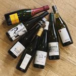 Seven bottles of wine arranged on a wooden surface.