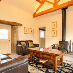 Cozy living room featuring a log burner, sofa, and coffee table.