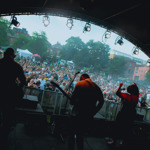 Shot from the back of band performing live on the Devonshire Green Stage as they look out on the crowd watching them below. 