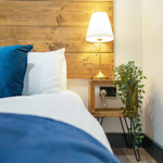 Side view of bed with a bedside table and a lit lamp.