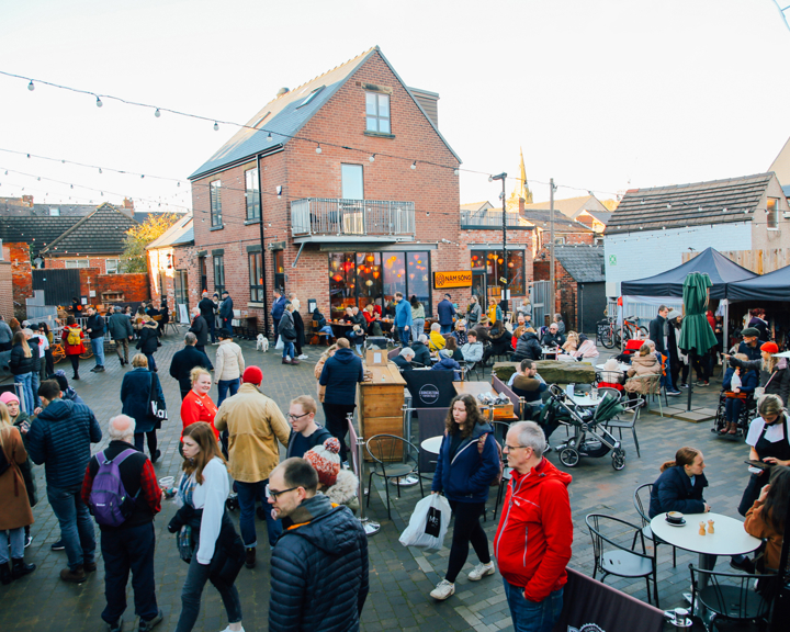 A large crowd of people looking round an outdoor market on Sharrow Vale Road in Sheffield.