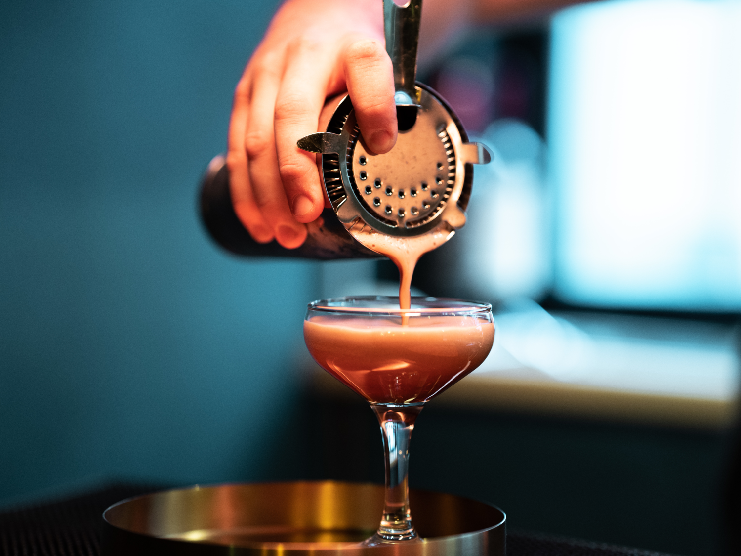 A cocktails being poured from a shaker.