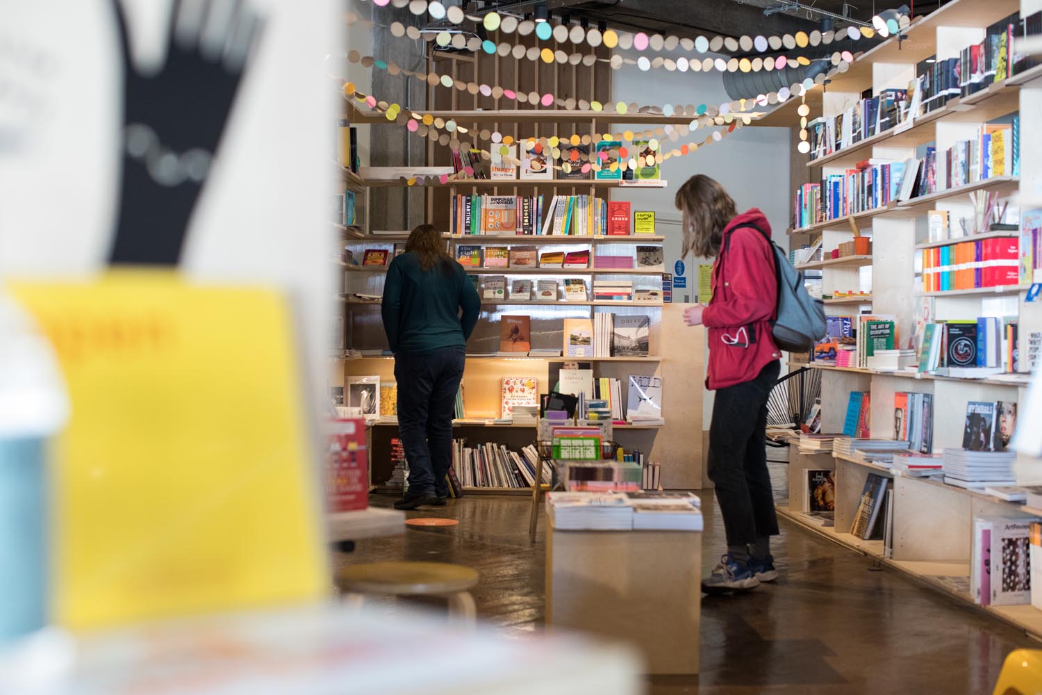 Inside the books and magazine specialist Labibliotek who are based in Kommune. People are browsing the shelves of books.